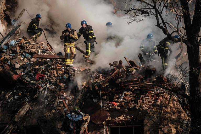 Bombeiros ucranianos trabalham em um edifício destruído em Kiev