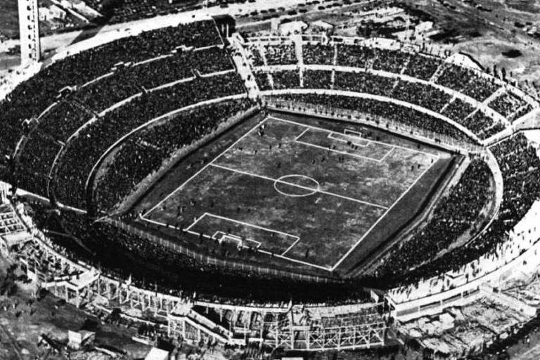 Foto em preto e branco mostra vista aérea do estádio Centenário, que está lotado