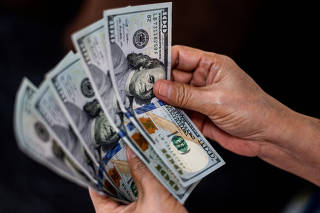 A person shows U.S. dollars at a currency exchange store in Manila