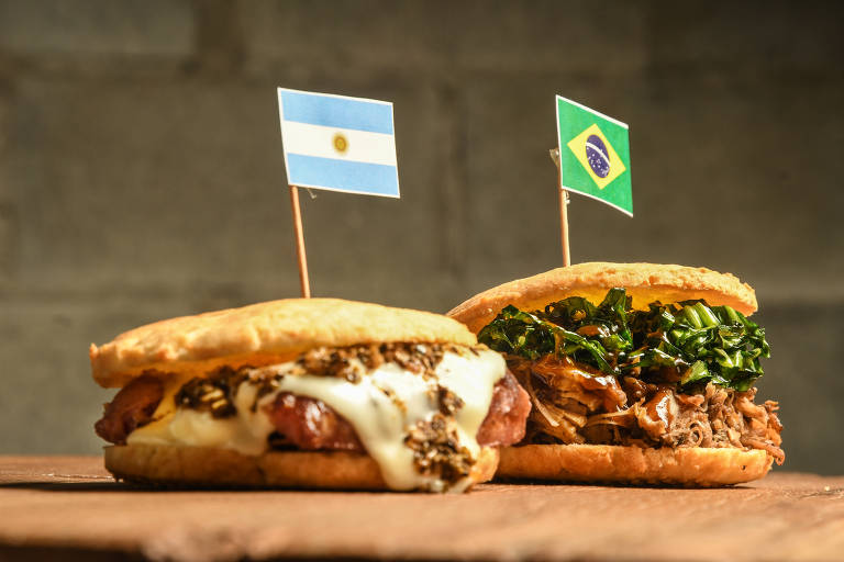 Foto mostra dois lanches em cima de uma mesa, um com a bandeira da Argentina e outro com a bandeira do Brasil