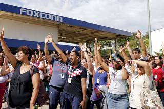 Brazilian Foxconn workers raise their arms as they vote during a metalworkers union assembly in front of the Foxconn plant in Jundiai