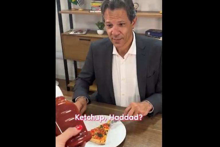 Fernando Haddad come pizza enquanto uma mão lhe oferece um tubo de ketchup