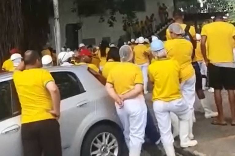 Funcionários de frigorífico Serradão/Frigobet, em Betim (MG), durante evento a favor de Jair Bolsonaro. Eles estão de costas, em pé, e vestem camiseta amarela 