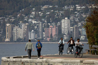 Cyclists ride on Stanley Park?s seawall, across from West Vancouver condominiums