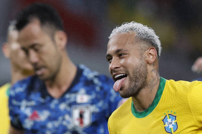 Com a língua à mostra, Neymar festeja gol do Brasil contra o Japão em amistoso em Tóquio; sua camisa é amarela e contém o escudo da CBF