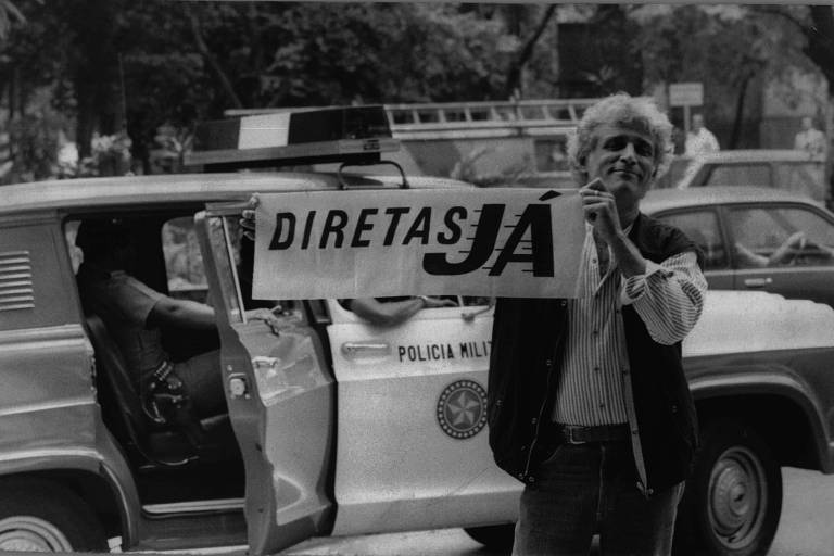O cartunista Ziraldo segura um cartaz pedindo 'Diretas Já' em retrato de 1984