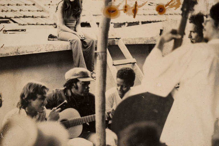Após feijoada e com Vilma a seu lado, Milton Nascimento ensaia ao violão acompanhado por Noveli ao contrabaixo