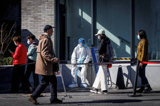 FILE PHOTO: A health worker wears a protective suit near a testing booth as outbreaks of coronavirus disease (COVID-19) continue in Beijing