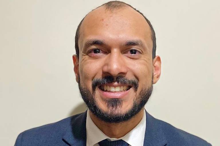 Foto do advogado Diogo Gradim, sorrindo e usando terno e gravata