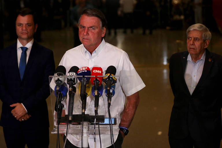 O presidente Jair Bolsonaro concede entrevista coletiva no Palácio da Alvorada. Ele é um homem branco, que veste uma camisa branca. Aos seus lados estão os ministros Anderson Torres (Justiça) e Augusto Heleno (GSI)