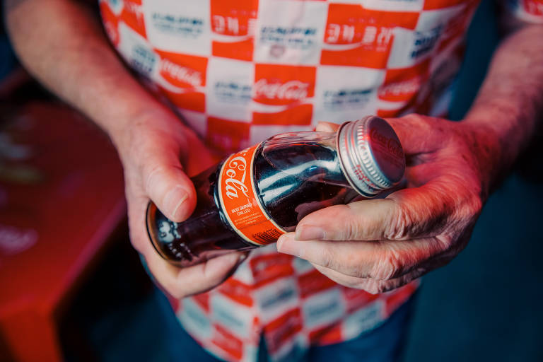 Homero Cesar Rodrigues exibe o primeiro item da Coca-Cola que ele coletou, uma garrafa especial que ele trouxe da sua viagem de lua de mel à Inglaterra, em 1982; sua coleção acaba de completar 40 anos