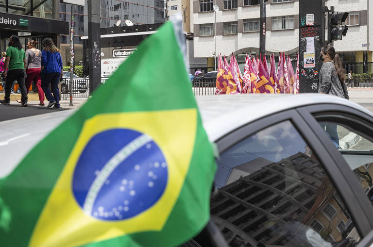 Carro com bandeira do Brasil em apoio a Bolsonaro cruza com bandeiras da campanha do Lula e Haddad na esquina da rua Carlos Sampaio com avenida Paulista 