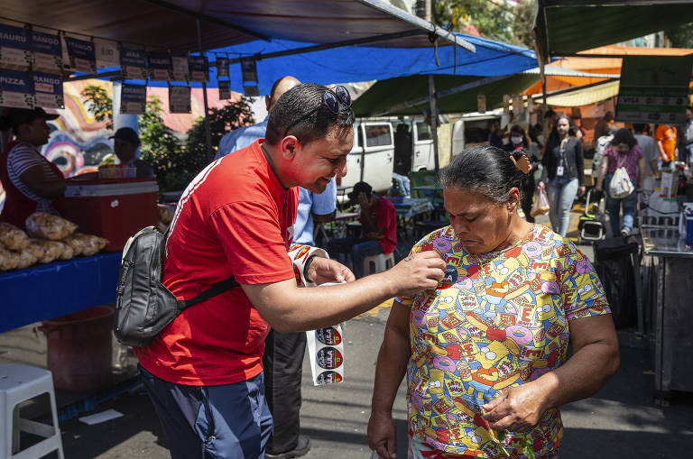 Homem faz panfletagem para Lula e Haddad em feira no bairro Bela Vista