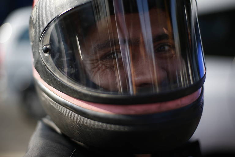 Motoboy de capacete sorri durante manifestação.
