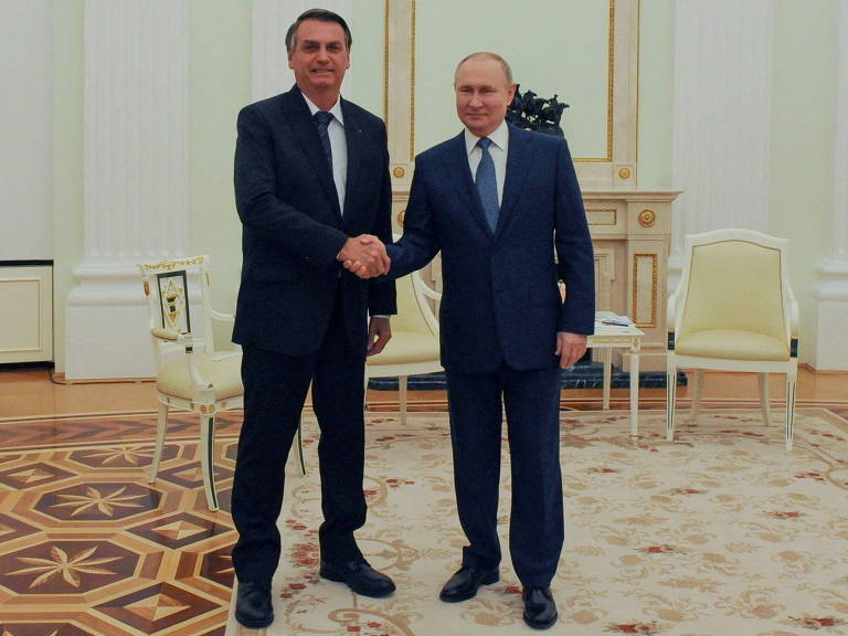 Ambos de pé e sorrindo, os presidentes do Brasil, Jair Bolsonaro, e da Rússia, Vladimir Putin, cumprimentam-se em encontro em Moscou