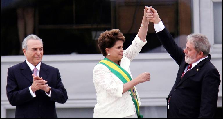 O ex-presidente Luiz Inácio Lula da Silva (PT) cumprimenta Dilma Rousseff (PT), que recebia a faixa presidencial em sua posse da presidente, com o vice-presidente Michel Temer (MDB) à esquerda