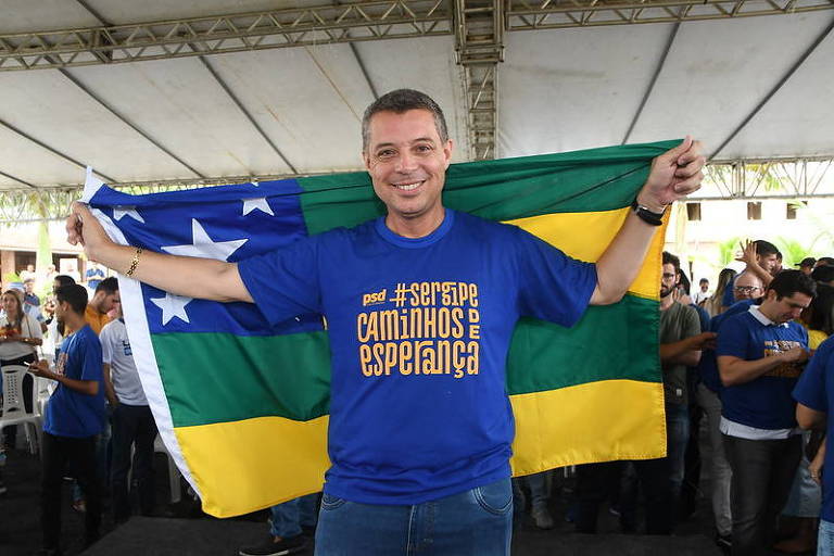 Fábio Mitidieri sorri e segura uma bandeira de Sergipe