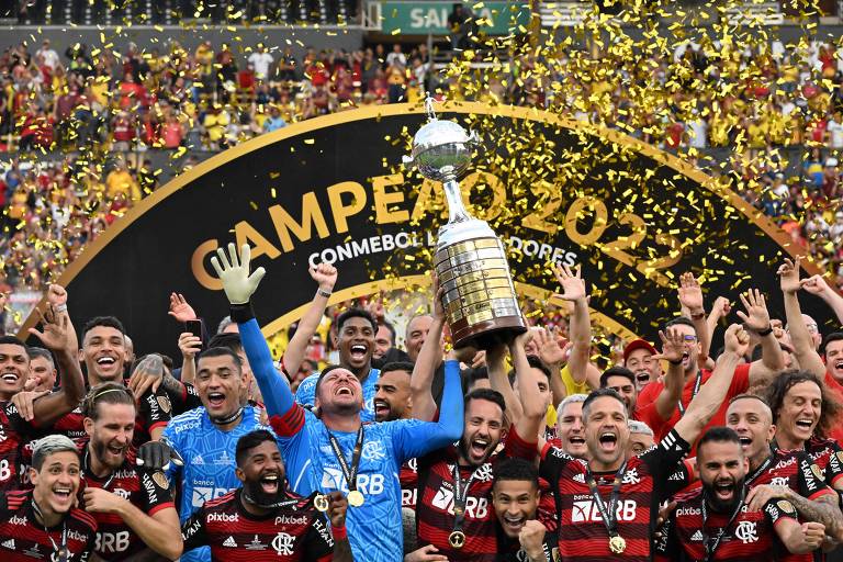 jogadores do Flamengo são vistos comemorando com a taça Libertadores da América 2022; chuva de papel picado dourado recai sobre o time 