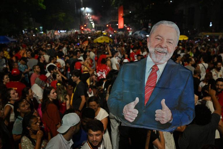 Apoiadores seguram cartaz com imagem do presidente eleito Luiz Inácio Lula da Silva (PT) durante a celebração da vitória do petista nas eleições do último domingo (30)