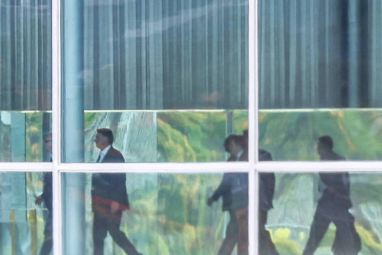 Vários homens caminhando por trás da janela do palácio. A frente, vestindo terno, Bolsonaro