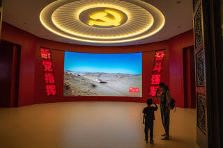 A young visitor salutes during a propaganda video for the PeopleÕs Liberation Army, at the Military Museum in Beijing, Sept. 2, 2022. (Gilles Sabrie/The New York Times)