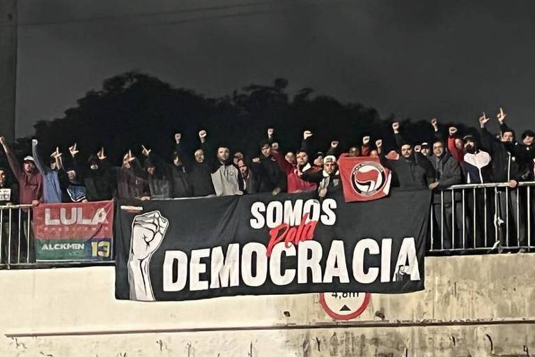 Imagem mostra um grupo de pessoas com uma faixa onde está escrito Somos Democracia