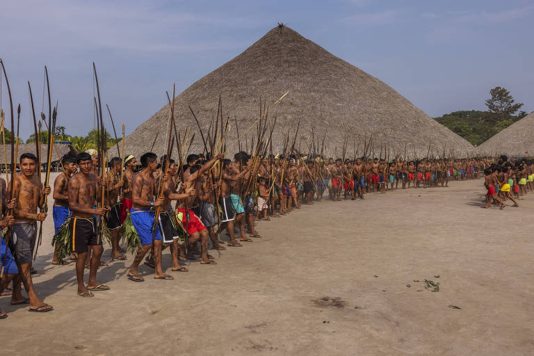 Aldeia com uma fila de indígenas munidos de lanças