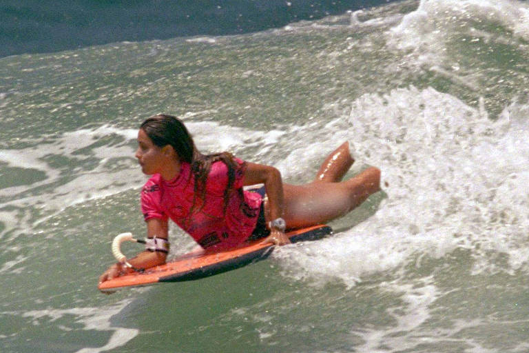 mulher deitada em uma prancha de bodyboard deslizando em uma onda