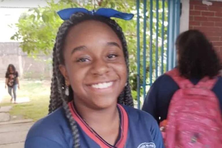 Luana Rafaela de Oliveira, de 12 anos, sorri para foto vestindo roupa escolar e um laço na cabeça