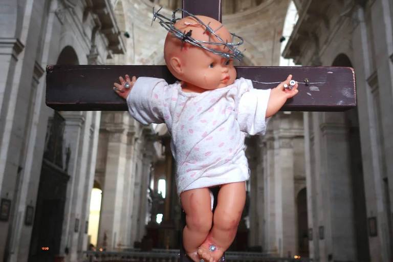 Um boneco infantil em forma de bebê aparece com uma coroa de espinhos e crucificado, em instalação artística que protesta contra abusos sexuais na igreja católica em Portugal