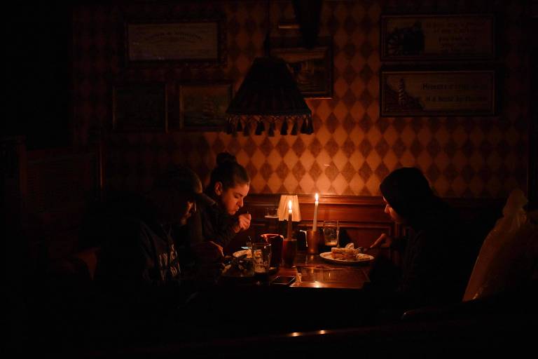 Moradores almoçam à luz de velas em um bar em Kiev devido a mais um blecaute na capital 