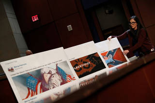 An aide puts out examples of Facebook pages, as executives appear before the House Intelligence Committee to answer questions related to Russian use of social media to influence U.S. elections, on Capitol Hill in Washington