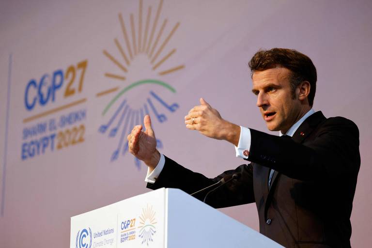 Em púlpito, Macron gesticula enquanto discurso; no painel ao fundo dele, há um logo da COP27