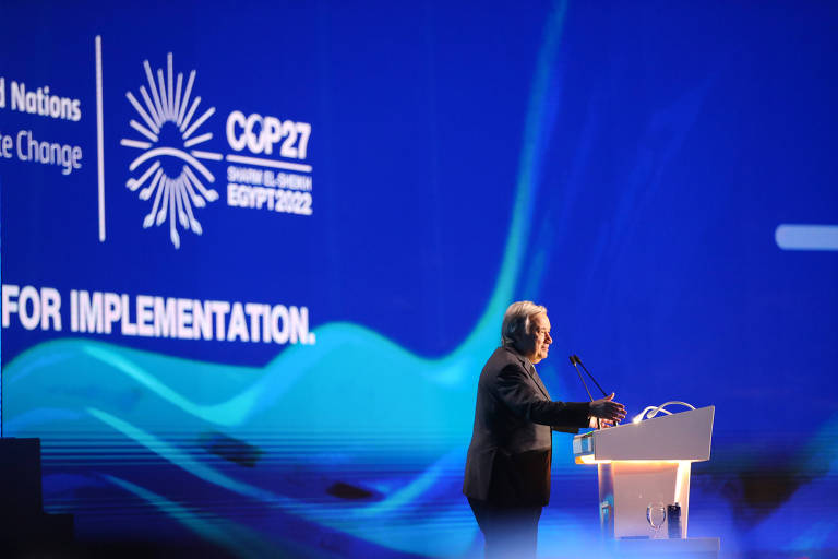 Homem em púlpito com painel azul com logo da COP27 ao fundo