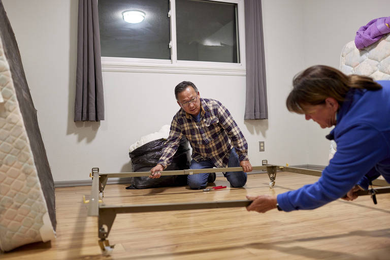 Jeff Chang, voluntário de uma instituição beneficente, monta com colega uma cama para imigrante no estado do Colorado, nos EUA