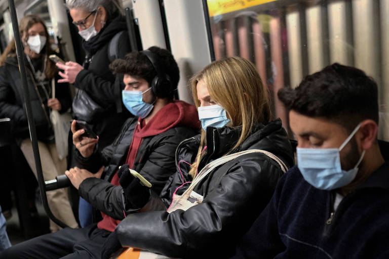 Pessoas sentadas no metrô de Barcelona com máscaras de proteção