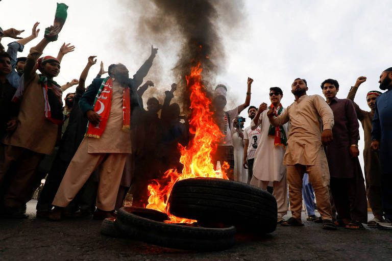 Manifestantes entoam palavras de ordem e incendeiam pneus, bloqueando avenida de Wazirabad, no Paquistão 
