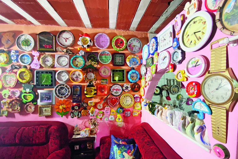 Sala com paredes cor-de-rosa coberta por relógios