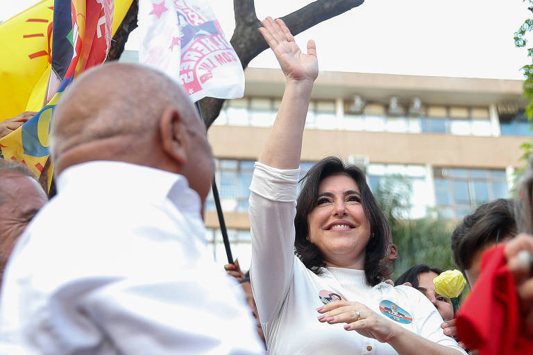 Simone Tebet acena com a mão direita erguida ao participar em Brasília de ato em apoio à candidatura de Lula à Presidência