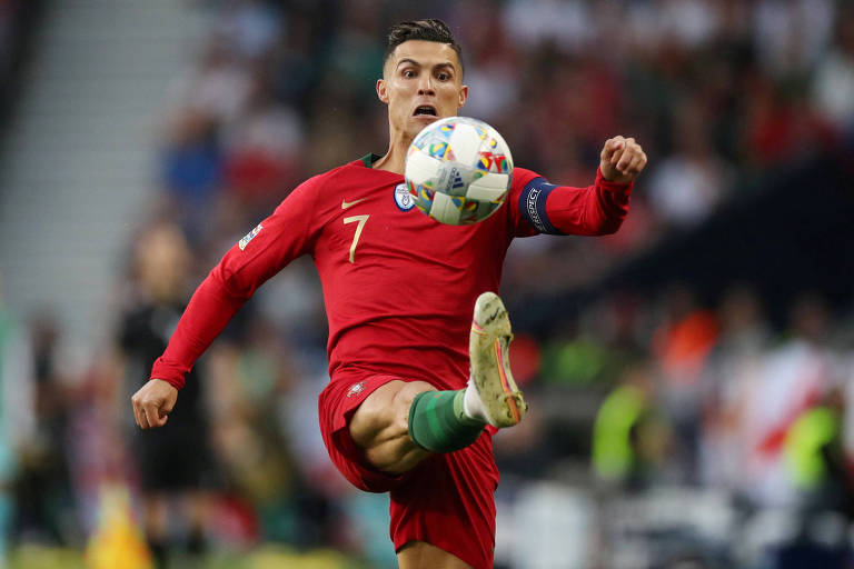Com a tarja de capitão no braço esquerdo e usando uniforme vermelho com o número 7, Cristiano Ronaldo tenta dominar a bola em jogo contra a Holanda na Liga das Nações; a bola está na altura do seu peito e ele está com a perna direita levantada, como se a estivesse chutando 