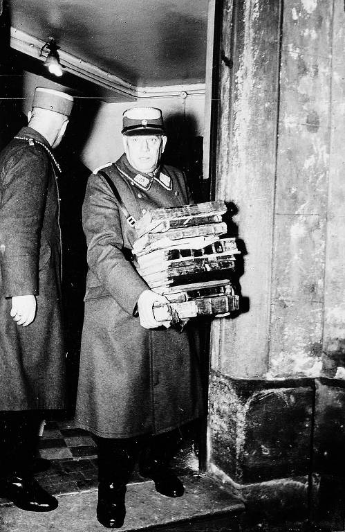 Fotografia até então desconhecida mostra membro do Sturmabteilung, a milícia paramilitar nazista, carregando pilha de livros judaicos, presumivelmente para serem queimados