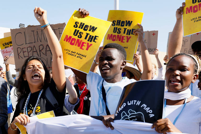 Jovens gritam e seguram cartazes com a mensagem 'show us the money' (nos mostre o dinheiro)