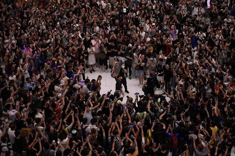 Multidão acompanha homem tocando tuba em um shopping de Shatin, em Hong Kong