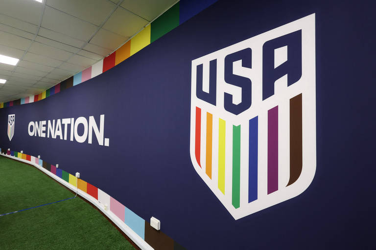 Esscudo da seleção dos EUA com a cores do arco-íris, em apoio às pessoas LGBTQIA+, em parede de sala usada para entrevistas da equipe em Al Rayyan, no Qatar