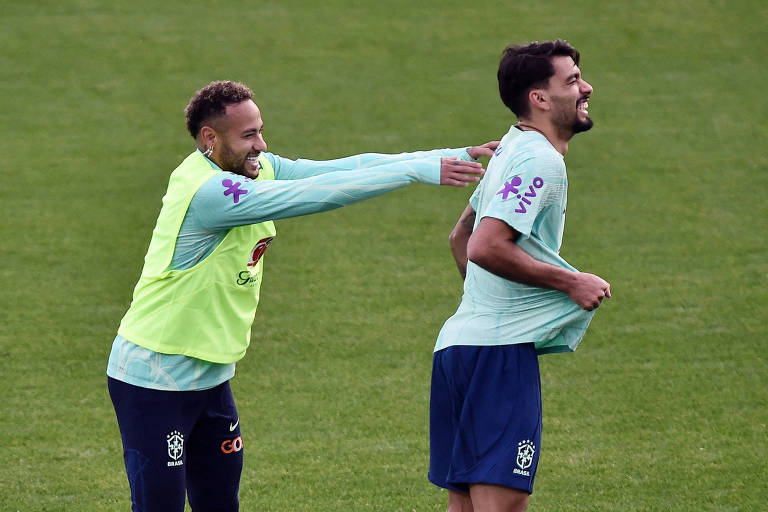 Neymar, sorrindo, coloca as mãos nas costas de Lucas Paquetá, que também sorri, em treino da seleção brasileira no centro de treinamento da Juventus, em Turim