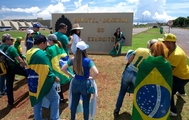 Envoltos na bandeira do Brasil, bolsonaristas fazem protesto antidemocrático contra o resultado das eleições presidenciais em frente ao quartel-general do Exército, em Brasília 