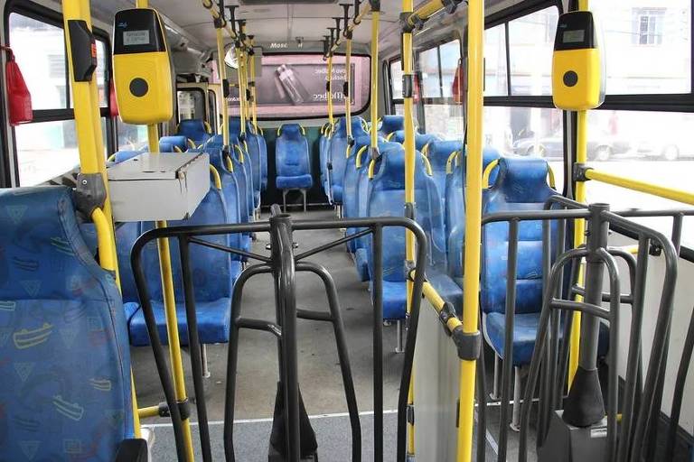 Interior de ônibus vazio, com bancos azuis e roletas pretas