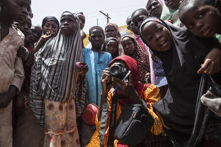 Children look on as Fati Abubakar takes photos of daily life at a market in Maiduguri, Nigeria, a regional capital where Boko Haram started out.