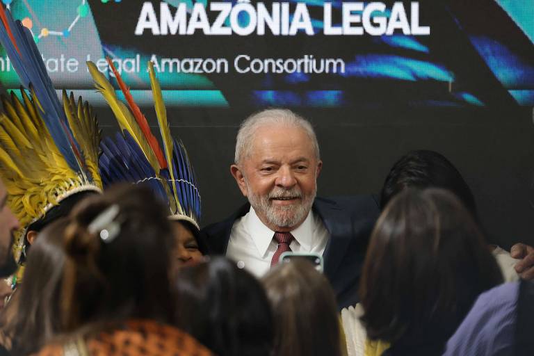Lula sorri entre público com painel escrito 'amazônia legal' ao fundo