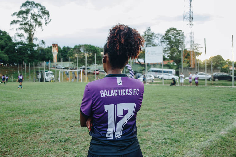 mulher negra de costas com a camiseta galácticos FC em campo de futebol